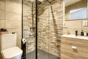 A bathroom with a shower, toilet, and vanity with a mirror.