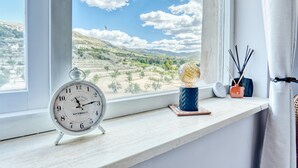 Une horloge Grand Café Riverdale posée sur un rebord de fenêtre, avec vue sur un paysage vallonné.