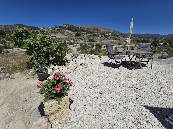 A patio with a table and chairs, surrounded by rocks and potted plants.