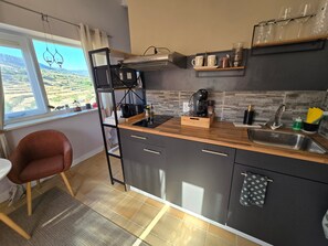 A compact kitchen with a wooden countertop, a built-in stove, a sink, and a window with a view of the countryside.