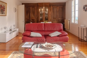 Una sala de estar con un sofá rojo, una mesa de centro de vidrio y armarios de madera.