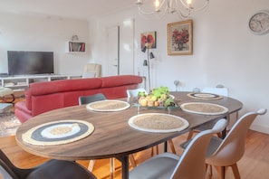 Un comedor con una mesa redonda, sillas, un televisor, un sofá rojo y adornos en la pared.