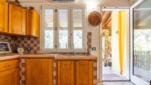 Una cocina con armarios de madera, una ventana y una puerta que da a un espacio exterior.