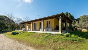 Een gelijkvloers huis met een overdekte veranda, een grindpad en een verzorgd gazon.