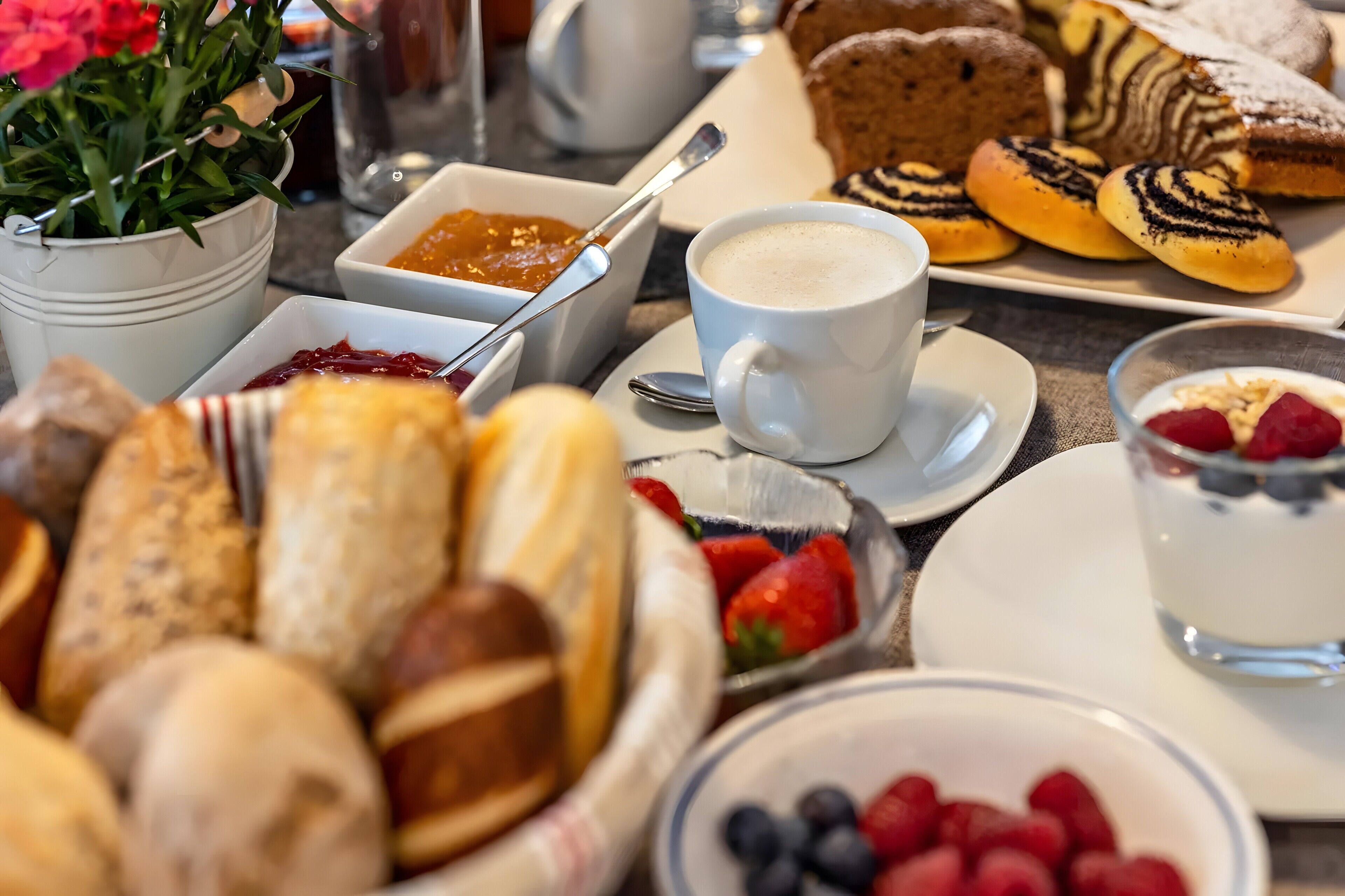 En morgenmad med kager, frugt og en kop kaffe.