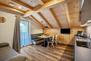 A cozy room with a wooden ceiling, a dining table with chairs, a sofa, and a TV mounted on the wall. - Apartment 'Krämerhof Apt Villnösser Geisler' with Mountain View, Shared Garden and Wi-Fi (Rodengo)