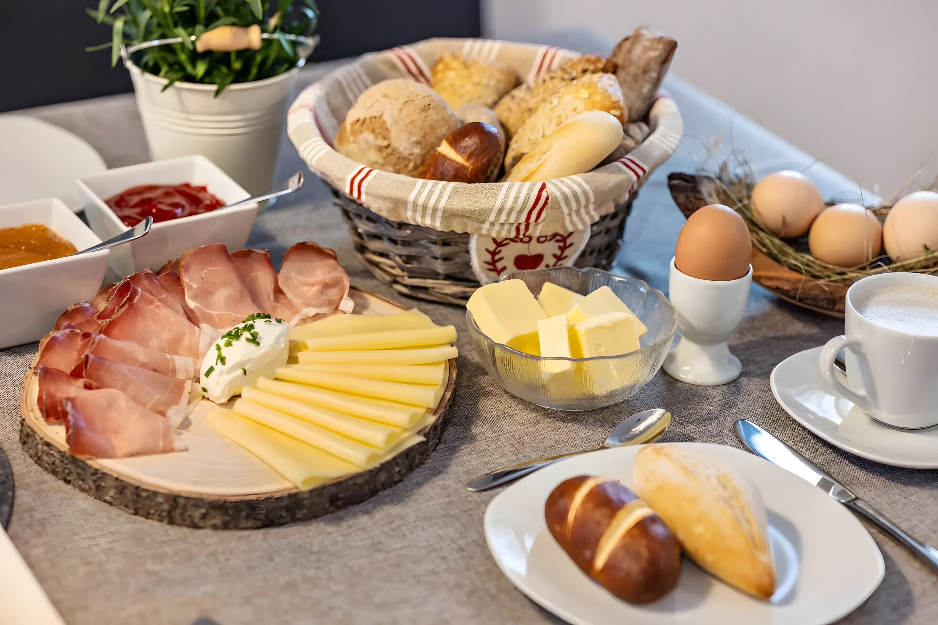 A breakfast setting with bread, eggs, ham, cheese, and pastries.