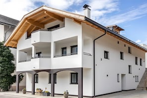 A multi-story building with balconies, a wooden roof, and a staircase. - Apartment 'Krämerhof Apt Villnösser Geisler' with Mountain View, Shared Garden and Wi-Fi (Rodengo)