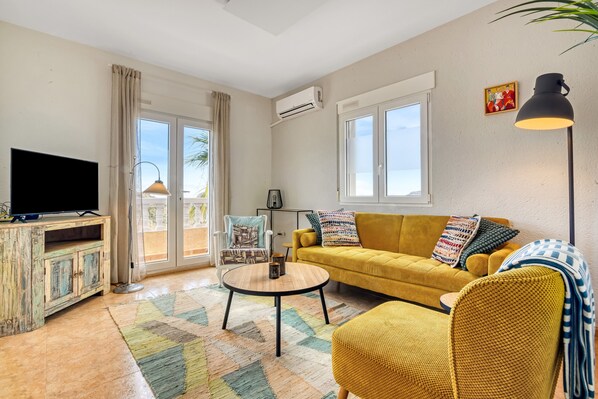 A living room with a sofa, a television, a round coffee table, and a chair.