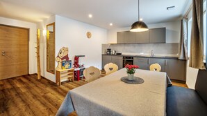 Una cocina compacta con electrodomésticos modernos, una mesa de comedor con un florero y una zona de estar acogedora.