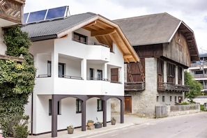 A modern two-story building with a balcony, solar panels, and stone walls. - Apartment 'Krämerhof Apt Peitlerkofel' with Mountain View, Shared Garden and Wi-Fi (Rodengo)
