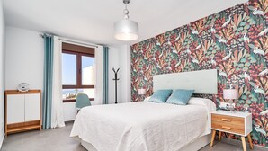 A bedroom with a bed, bedside table, lamp, and a window with curtains. - 'El Ático Del Oasis' Apartment with Sea Views, Wi-Fi, and Air Conditioning (Salobreña)