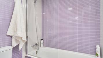 Un baño con ducha de vidrio, una bañera blanca y paredes con azulejos morados.