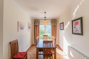 Un comedor con mesa y sillas, una lámpara colgante y cortinas.