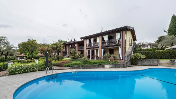 A swimming pool with a clear blue water surface, surrounded by a paved deck.