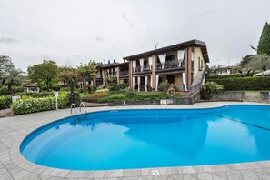 A swimming pool with a clear blue water surface, surrounded by a paved deck. - Apartment 'Residence La Piopa' with Mountain View, Wi-Fi and Air Conditioning (Polpenazze del Garda)