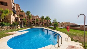 A swimming pool with a lifebuoy, a clear sky, and a building with balconies. - Apartment 'Coto Real' with Sea View, Wi-Fi and Air Conditioning (Manilva)