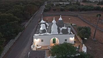 A white building with conical roofs, a paved road, and surrounding vegetation.