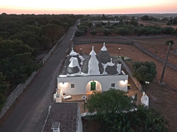 A white building with conical roofs, a paved road, and surrounding vegetation.