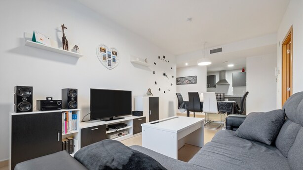 Un salon moderne avec un canapé, un téléviseur, des haut-parleurs et une table basse.