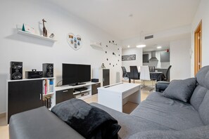 A modern living room with a sofa, TV, speakers, and a coffee table.