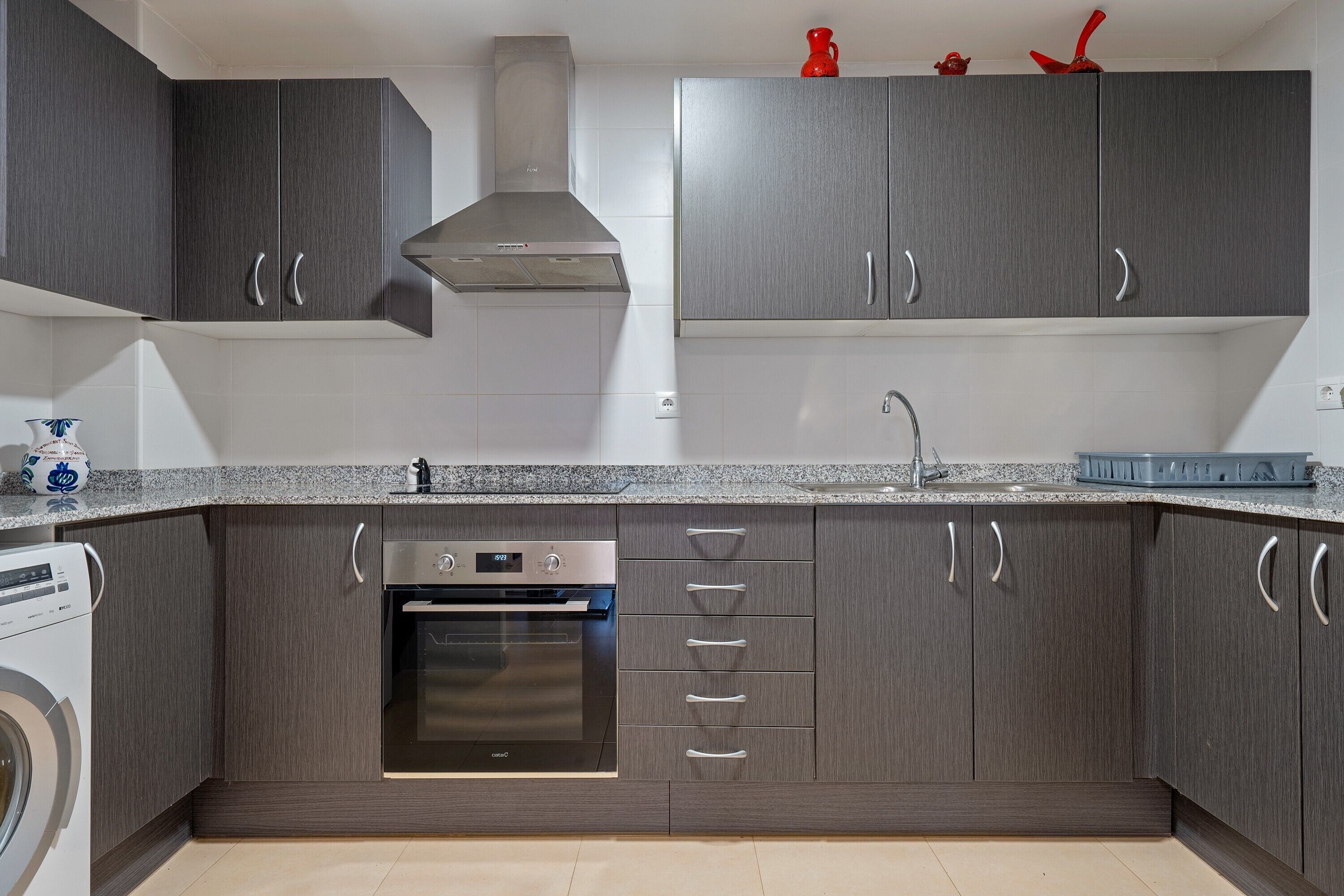 Een moderne keuken met donkere kastjes, een roestvrijstalen afzuigkap en een inbouwoven.