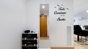 Une chambre moderne équipée d’une armoire, d’un miroir, d’un mur orné d’un texte motivant et d’une chaise noire.