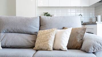 Un canapé gris avec trois coussins, dans une cuisine au décor moderne.