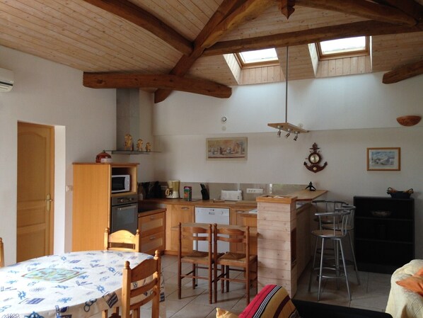 Une cuisine avec des poutres en bois, une table à manger avec des chaises, un four à micro-ondes et une cuisinière.