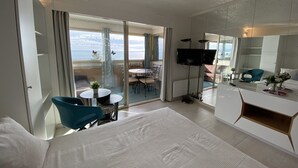 Una habitación de hotel moderna con balcón, zona de comedor y televisor.