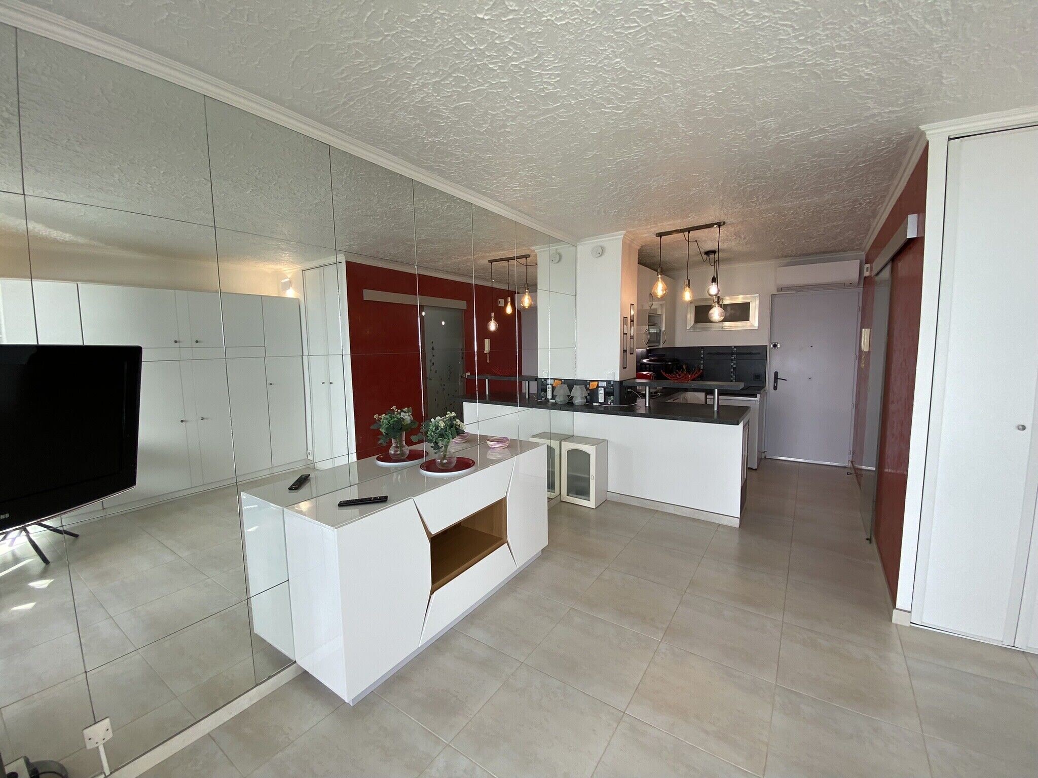 A modern kitchen with white cabinetry, a central island, and pendant lighting.
