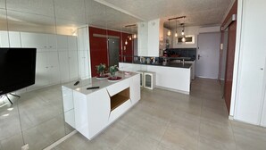 Una cocina moderna con armarios blancos, una isla central e iluminación colgante.