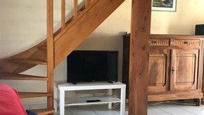 En trappe, et fjernsyn på et hvidt stativ, et skab og en rød sofa.