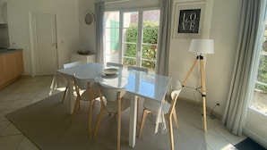 A dining area with a table, chairs, a lamp, and a view of greenery outside. - Holiday Home 'Vacances Au Château D'Oléron' with Private Terrace and Wi-Fi (Le chateau d'oleron)