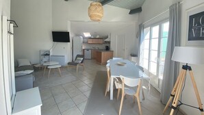A modern kitchen with a dining area, a television, and a large window. - Holiday Home 'Vacances Au Château D'Oléron' with Private Terrace and Wi-Fi (Le chateau d'oleron)