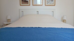 A bed with a white and blue bedspread, a white headboard, and three framed pictures on the wall. - Holiday Home 'Vacances Au Château D'Oléron' with Private Terrace and Wi-Fi (Le chateau d'oleron)