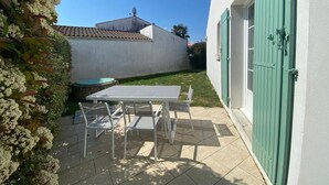 A patio with a table and chairs, a green door, and a white wall. - Holiday Home 'Vacances Au Château D'Oléron' with Private Terrace and Wi-Fi (Le chateau d'oleron)