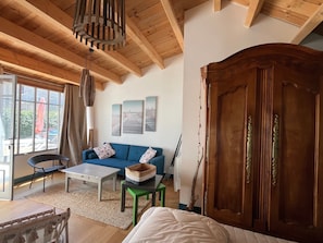 Una habitación con techo de madera, un sofá, una mesa, una cama y un amplio armario de madera.