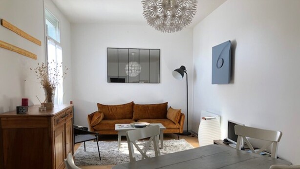 Un salon moderne comprenant un canapé, une table à manger, des chaises, un meuble et un luminaire décoratif au plafond.