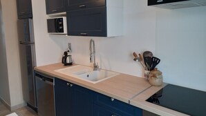 Una cocina moderna con un lavamanos doble, electrodomésticos de acero inoxidable y armarios color azul oscuro.
