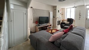 Una sala de estar con sofá, televisión, chimenea y una escalera.
