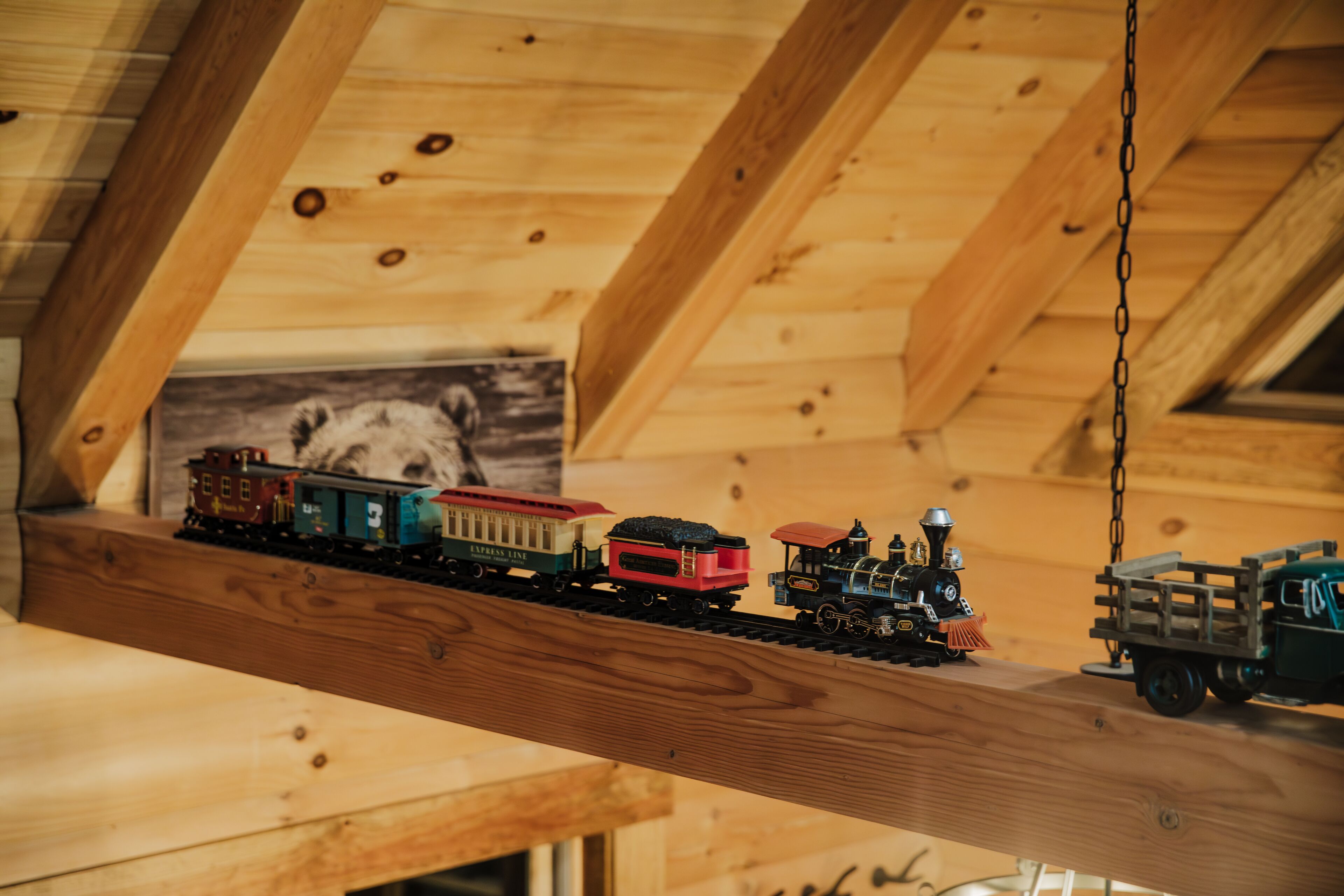 A wooden ceiling with a wooden beam supporting a model train set.