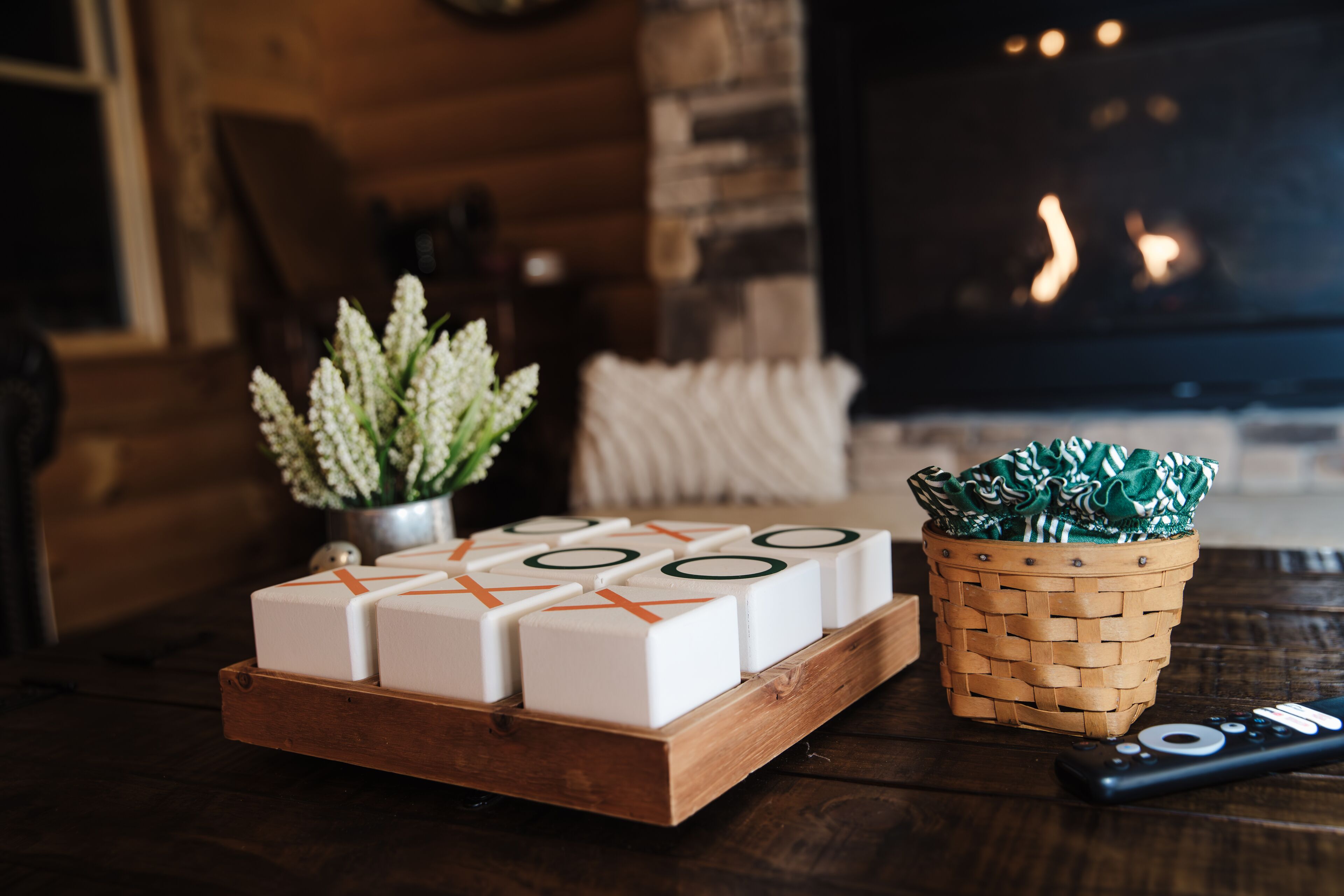 A wooden tray with white blocks, a woven basket, and a remote control on a dark wooden table.