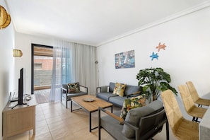 A modern living room with a sofa, a coffee table, a TV, and a plant.
