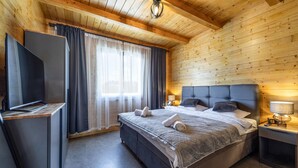 Een hotelkamer met een bed, een televisie, een bureau en een raam met gordijnen.