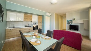 Una cocina moderna con armarios de madera, una mesa de comedor preparada para cuatro personas y un sofá rojo en la sala de estar.