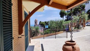 Un espacio exterior cubierto con vista a una campanario, una entrada protegida por una reja y una maceta de terracota.