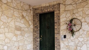 Un muro in pietra con una porta verde e una ruota decorativa.
