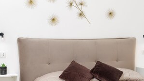Una camera da letto con una testiera trapuntata, due cuscini marroni, un materasso bianco e decorazioni a parete.
