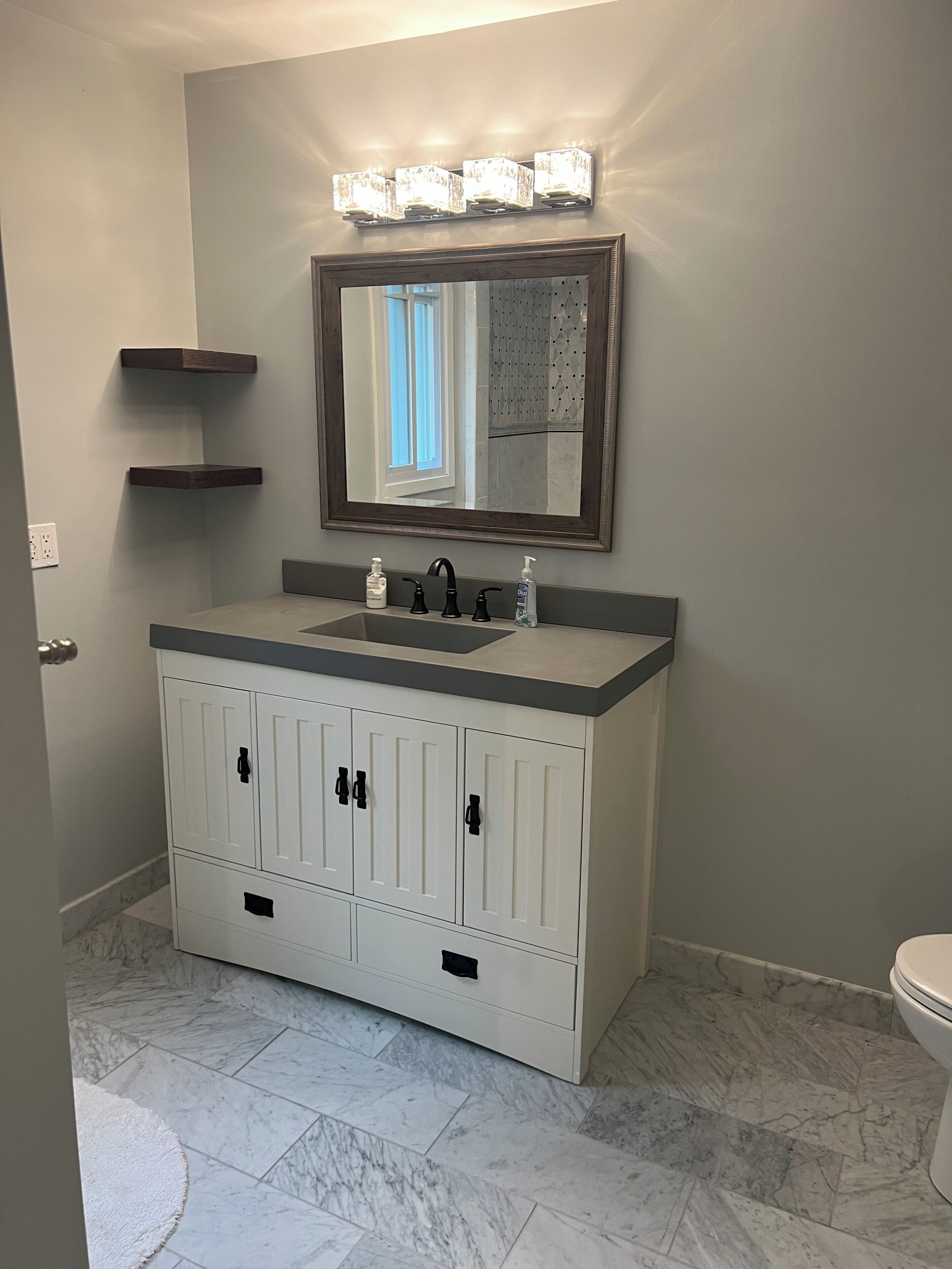 A bathroom with a white vanity, a mirror, and a toilet.